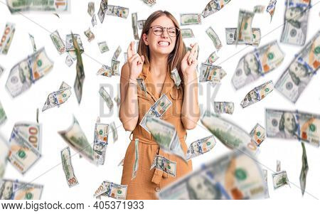 Young beautiful blonde woman wearing casual clothes and glasses gesturing finger crossed smiling with hope and eyes closed. luck and superstitious concept.