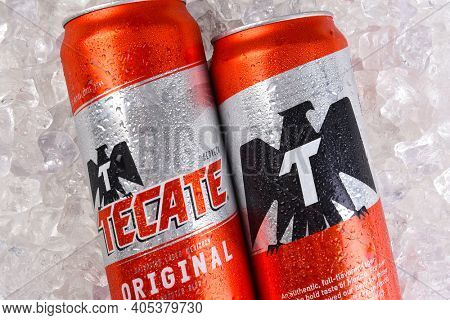 IRVINE, CALIFORNIA - MARCH 21, 2018: Two Tecate Original Cerveza cans on ice closeup. Cuauhtemoc Moctezuma Brewery is a major brewer based in Monterrey, Nuevo Leon, Mexico, founded in 1890.