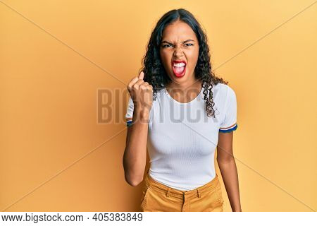 Young african american girl wearing casual clothes angry and mad raising fist frustrated and furious while shouting with anger. rage and aggressive concept. 