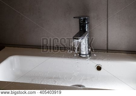 Broken Water Faucet In The Bathroom Sink. Water Splashes From The Silver Faucet