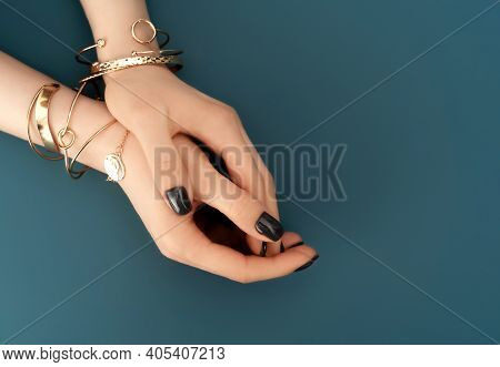 Female Hands With Trendy Dark Nail Design With Gold Bracelets On Aqua Background. Luxury Concept. Fe