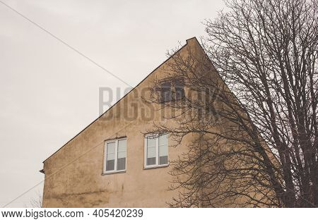 A Part Of Yellow Brown Sanstone House Facade With Roof And A Tree In Front Of It. Street View Citysc