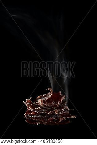 Dried Deer Meat. Thin Planks With Curled Edges, Shaped Like A Pyramid, And A Plume Of Smoke Emanatin