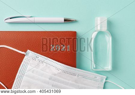2021 Year Red Leather Diary, Pen, Small Bottle Of Hand Sanitizer And Disposable Medical Face Mask On