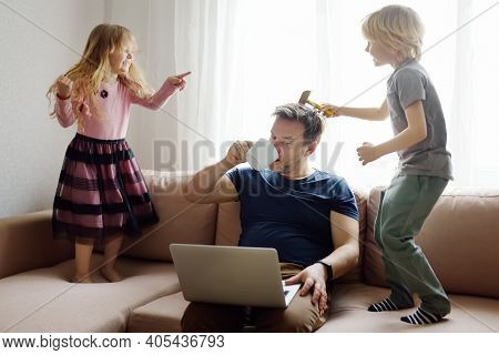 Tired Father With His Two Kids During Quarantine. Home Office Concept. Online Working And Household 