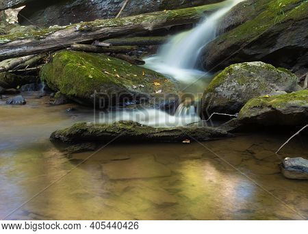 Waterfall Near Boone In North Carolina That Is Running Over Moss Covered Roccks And A Large Log.