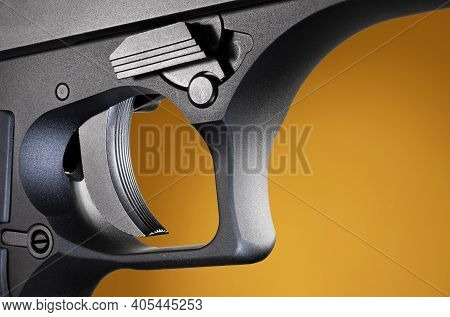 Metal Trigger For A Very Large Semi-automatic Pistol On A Brown And Orange Background