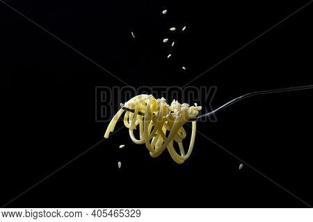 Spaghetti On A Black Background. Boiled Spaghetti On A Fork. Isolated Spaghetti. Sesame Seeds Are Po