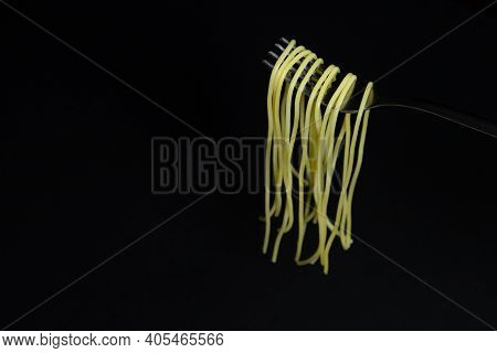 Spaghetti On A Black Background. Boiled Spaghetti On A Fork. Isolated Spaghetti. Spaghetti Hanging O