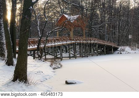 Picturesque Landscape View Of Old Wooden Bridge Over The Frozen Lake In The Village Of Pushcha-vodit