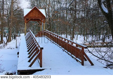 Winter Season In The Pushcha-vodytsia. Picturesque Landscape View Of Old Wooden Bridge Over The Froz