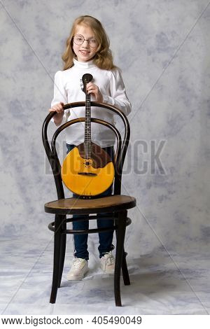 Cute Little Girl Learning To Play The Plucked Musical Instrument, Domra.