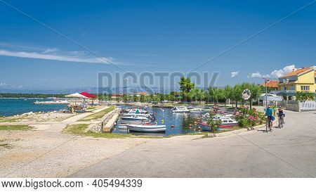 Zaton, Croatia, July 2019 Cyclist Passing Small Marina With Moored Motorboats In Zaton Bay. Families