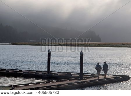 Waldport, Oregon, Usa, Date 08-05-2012 Couple Enjoying A Romantic Evening Walk On A Waldport Pier On