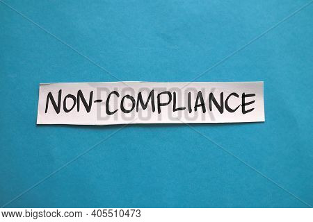 Non Compliance, Text Words Typography Written On Paper Against Blue Background, Life And Business Mo