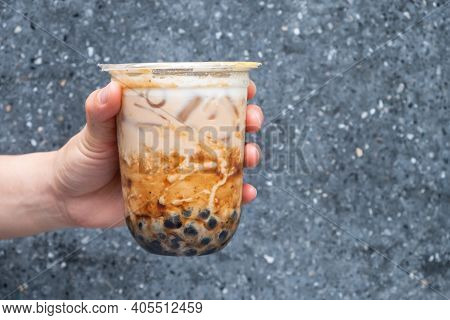 Cropped Shot Of Someone Hand Holding A Cup Of Iced Bubble Milk Tea. Bubble Tea Was A Traditional Dri