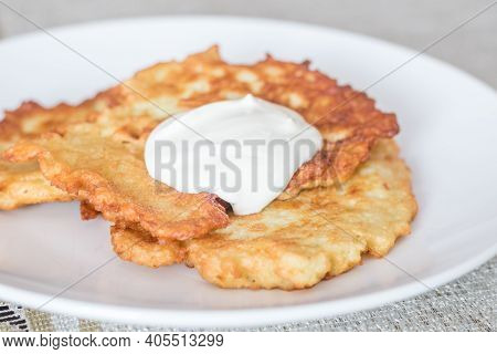 Polish Potato Pancakes Served With Sour Cream. Polish Traditional Placki Ziemniaczane On White Plate