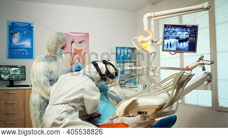 Dental Technician In Protective Equipment Lighting The Lamp For Examining Child Patient During Covid