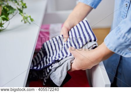 Close Up Of Woman Folding Up Clothes And Tidying Them Into Drawers