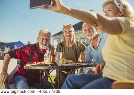 Group Of Cheerful Senior People Taking A Selfie While Having Lunch In The Backyard By The Pool, Gath