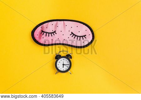 Sleep Concept Showing An Eye Mask And An Alarm Clock On A Yellow Background. Copy Space