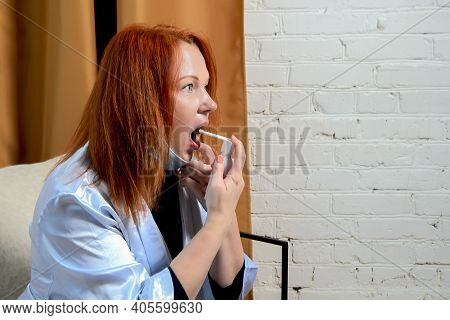 Young Red-haired Woman Treats Throat Spray. Concept: Treatment Of First Signs Of Cold, Seasonal Vira