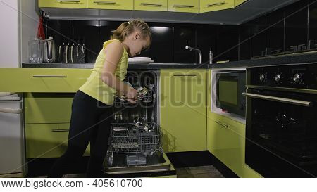 Smart Girl Learning To Use Dishwasher. Stylish Modern Built In Kitchen Appliances In Green Black. Ch