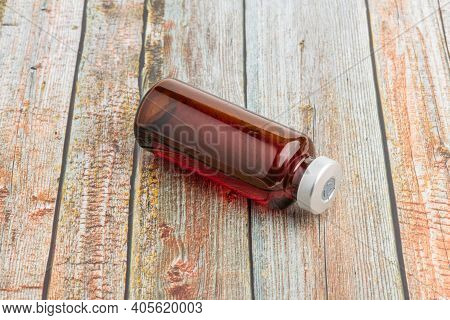 A Macro Shot With Selective Focus Of An Amber Color Vaccine Injection Vial Set On A Wood Background.