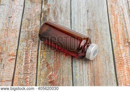 A Macro Shot With Selective Focus Of An Amber Color Vaccine Injection Vial Set On A Wood Background.