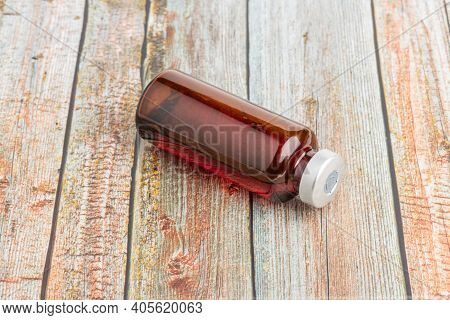 A Macro Shot With Selective Focus Of An Amber Color Vaccine Injection Vial Set On A Wood Background.