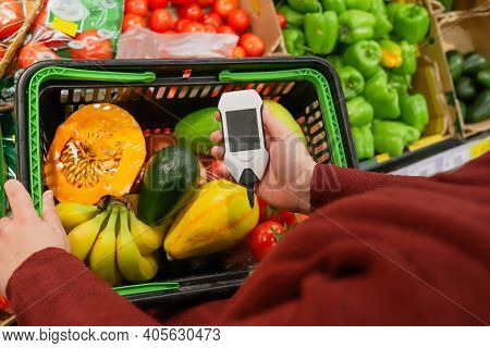 Measurement Of Nitrate Levels In Vegetables And Fruits. Hand Holding Nitrate Tester On A Supermarket