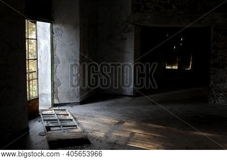 Empty Abandoned Room With Broken Door And Dramatic Bright Sunlight Entering The Place