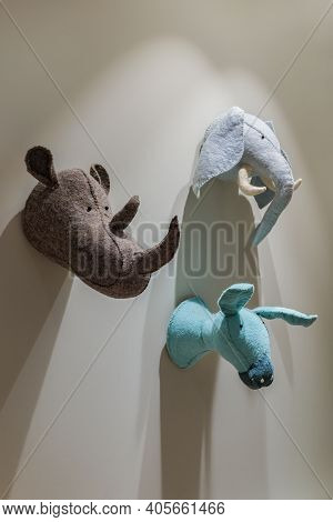 Felted Animals Toys Hanging On The Wall. Heads Of Donkey, Rhinoceros And Elephant On Gray Wall. Emul