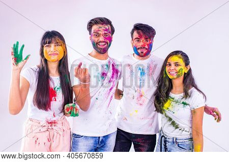 Four Indian Students Painted In Colors Celebrating Holi Festival In Studio White Isolate Background