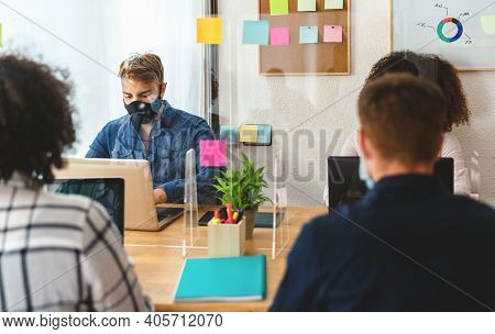 Young People In Co-working Creative Space Wearing Surgical Mask And Keeping Social Distance To Avoid