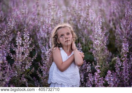 Close-up Portraits Of A Little Girl With Long Flowing Hair In Blooming Pink Sage Field. Dreamer Blon