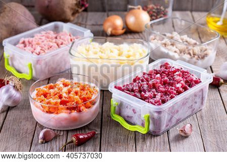 Assortment Of Frozen Vegetables In Containers On A Wooden Table. Frozen Food