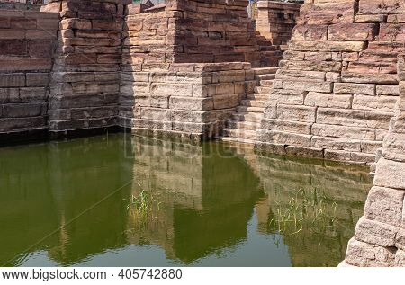 Aihole, Karnataka, India - November 7, 2013: Weeds Grow In Greenish Water Of Chakra Gudi Tank With B