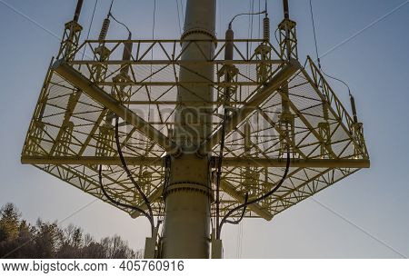 Low Angle View Of Grid Support Of Large Electrical Tower With Sun Shining From Behind Tower.