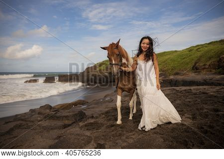 Woman Leading Horse By Its Reins. Horse Riding On The Beach. Human And Animals Relationship. Asian W