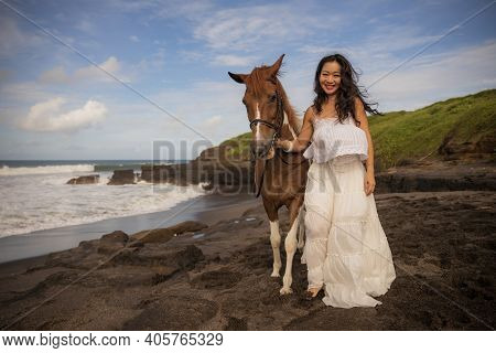 Happy Woman Leading Horse By Its Reins. Horse Riding On The Beach. Human And Animals Relationship. A