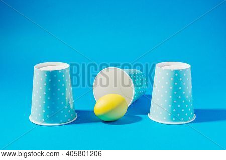 Colored Easter Eggs On Colored Background, Shell Game With Paper Cups And Colored Egg
