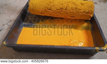 A Man Pours Yellow Paint Into A Tray. Yellow Paint Slowly Pours Into Black Paint Tray. Wall Painting