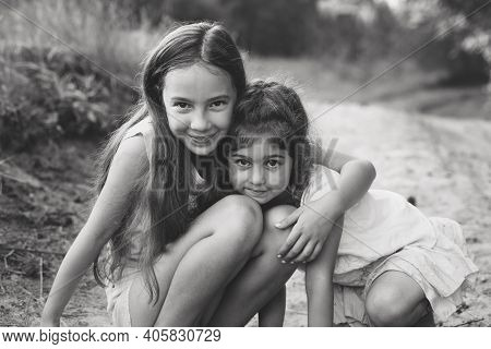 Black And White Portrait Of Two Cute Little Girls Embracing And Laughing At The Forest. Happy Kids O