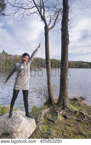 A Chinese Woman Standing On A Rock Near Water Within Burr Pond State Park In Torrington Connecticut 