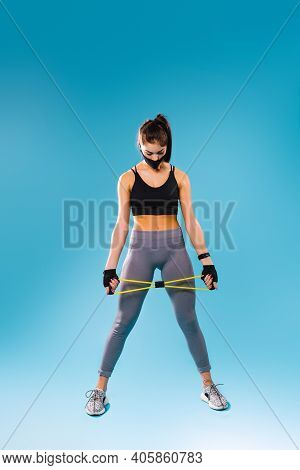 A Full-length Photo Of A Pumped-up Girl In A Protective Black Mask And With A Resitance Band In Her 