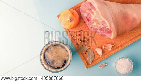 Raw Pork Knuckle, Garlic, Onion, Dried Bay Leaves, Sea Salt And Peppercorns On Wooden Cutting Board.