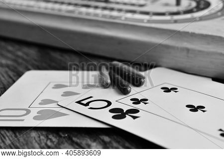 A Close Up Image Of Two Playing Cards With Cribbage Pegs And Cribbage Board.