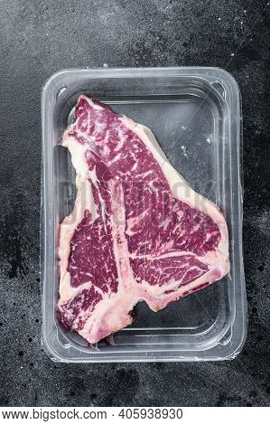 T-bon Raw Beef Steak In Vacuum Packaging. Black Background. Top View
