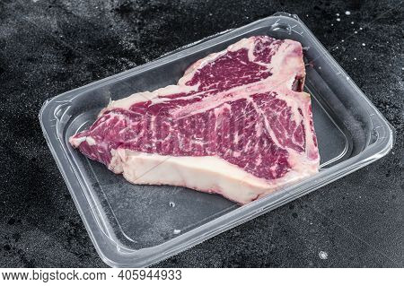 T-bon Raw Beef Steak In Vacuum Packaging. Black Background. Top View
